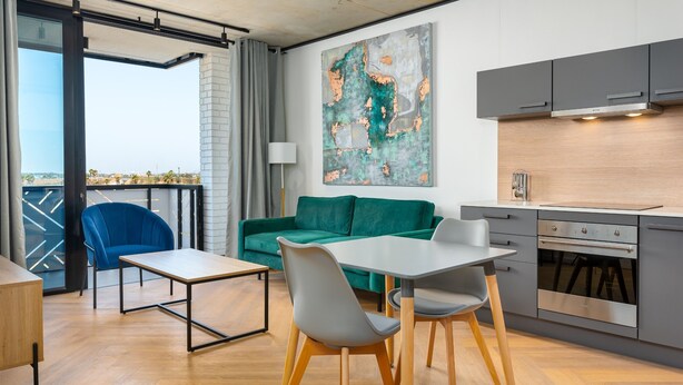 A modern kitchen with grey cabinets, a wooden countertop, and a large painting on the wall. - Bridgewater One  | Netflix | Fibre (Cape Town)