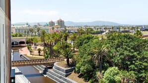 A view of a hotel with a river, palm trees, and a bridge. - Bridgewater One  | Netflix | Fibre (Cape Town)