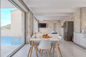 Una cocina moderna con una pared de piedra, un ventanal grande y un comedor con una mesa lista para dos personas.