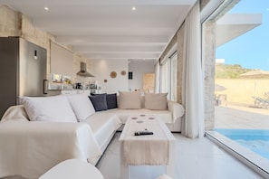 Una sala de estar moderna con un sofá, una mesa de centro y vista a una piscina.