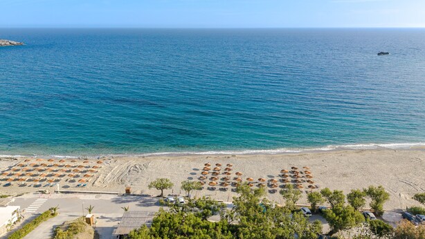 A beach with umbrellas, a parking area, and a view of the sea.