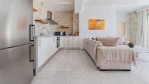 A modern kitchen with a stone wall, a large bed, and a painting on the wall.