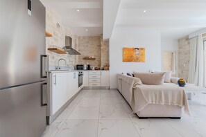 A modern kitchen with a stone wall, a large bed, and a painting on the wall.