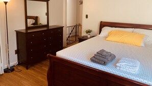 A neatly arranged bedroom with a bed, a dresser, a mirror, and a lamp. - Private Queen Bedroom Garvin (Sharon Hill)