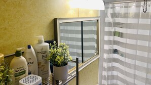 A bathroom with a yellow textured wall, a mirror with a striped curtain, and various toiletries on a shelf. - Private Queen Bedroom Garvin (Sharon Hill)