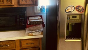 A kitchen with wooden cabinets, a black microwave, a red tray, and a stainless steel refrigerator with a water dispenser. - Private Queen Bedroom Garvin (Sharon Hill)