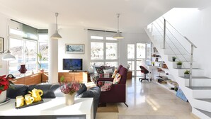 Un salon spacieux doté d’un escalier moderne, de grandes fenêtres et d’un coin salon confortable.
