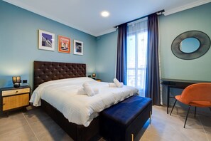 Un dormitorio con una cama grande, un escritorio y una silla. Hay tres cuadros en la pared.