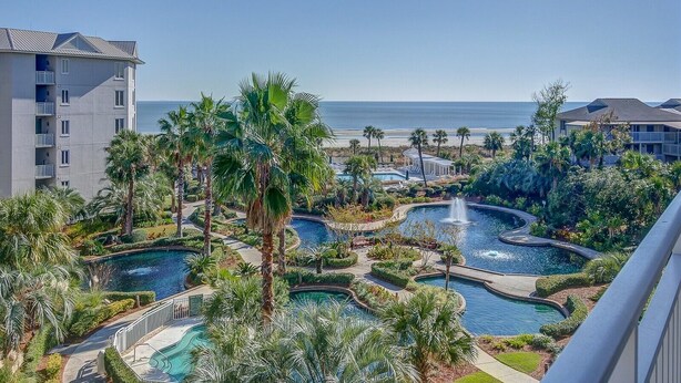 Un resort con varias piscinas, palmeras y vista al océano.