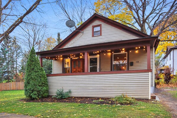 A single-story house with a gabled roof, a front porch with string lights, and a satellite dish.