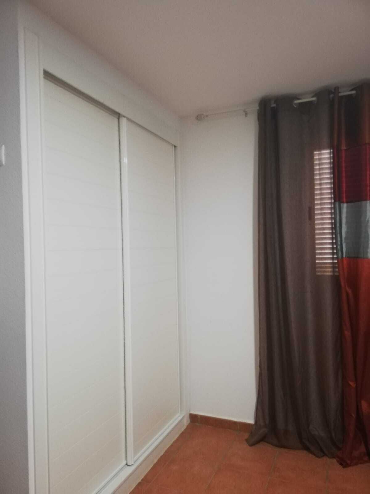 A room with a sliding closet door, a window with blinds, and a tiled floor.