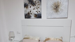A neatly made bed with striped bedding and two pillows, a bedside table with a lamp, and two wall art pieces above the bed. - NATURIST DUPLEX IN FIRST LINE OF VERA PLAYA! (Vera)