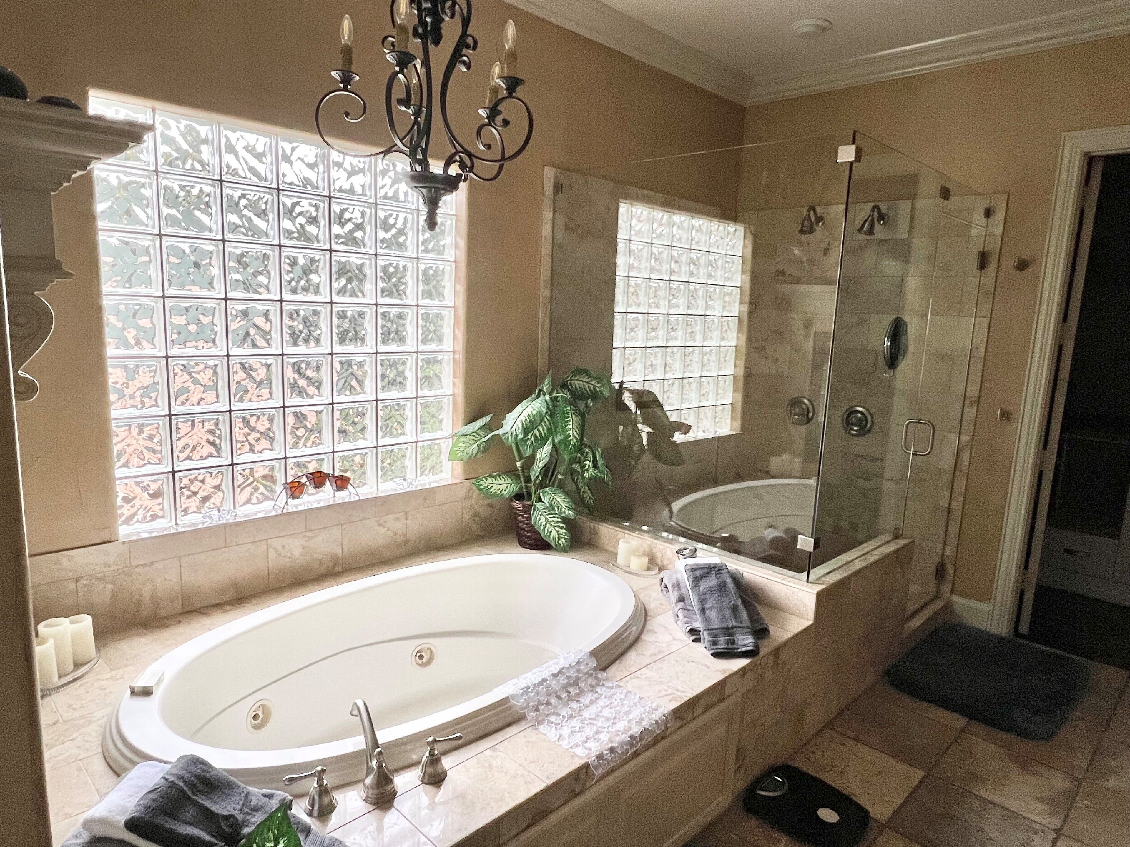 A bathroom with a large bathtub, a shower, and a window with decorative glass panels.