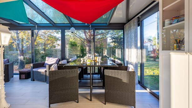 A covered outdoor seating area with wicker furniture and a glass table, overlooking a garden. - Gawa's House - Maison avec jardin proche mer (Meschers-sur-Gironde)