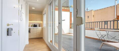 Un apartamento moderno con cocina, un balcón con mesa y sillas, y vistas a la ciudad.