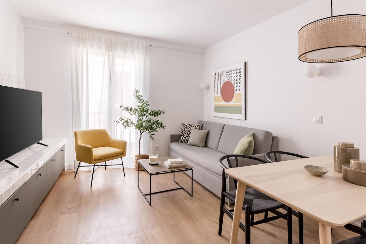 A modern living room with a sofa, a yellow armchair, a coffee table, and a dining table.