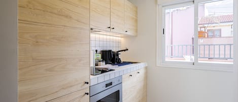 A compact kitchen with wooden cabinets, a built-in oven, and a window providing natural light.