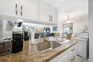 A modern kitchen with white cabinets, a stainless steel sink, a Keurig coffee maker, and a toaster. - Apt#2 BEACH-CHARMING Lodging SUNNY PLACE:BBQ/Patio (Pompano Beach)