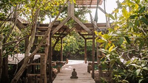 A wooden structure with a Buddha statue at the end of a pathway surrounded by lush greenery. - Uman Glamping & Cenote Tulum (Tulum)