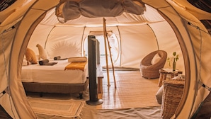 A tent with a bed, pillows, a chair, a small table, and a plant. - Uman Glamping & Cenote Tulum (Tulum)