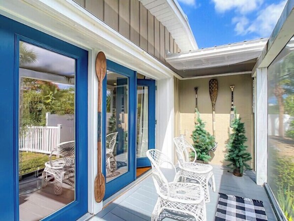 Relax in this serene outdoor space, featuring a glass door, wicker chairs, and a small table.