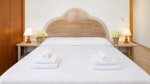 A hotel room with a wooden headboard, two bedside tables with lamps and flower pots, and two neatly folded towels on the bed. - Villa Roca Nova - Four Bedroom Villa, Sleeps 8 (Cala d'Or)