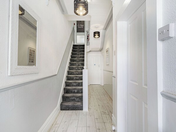 A staircase with a handrail, a light fixture above, and a door at the bottom.