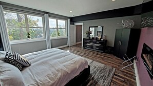 A modern bedroom with a large bed, a dresser, and a mirror.