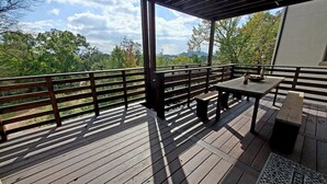 A wooden deck with a railing, a table, and a grill area.