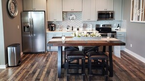 A modern kitchen with white cabinets, a stainless steel refrigerator, a microwave, and a central island with seating.