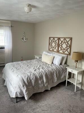Un dormitorio con cama, mesitas de noche, lámpara y decoración en la pared.