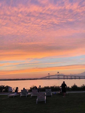 A sunset view over a body of water with a bridge in the distance.