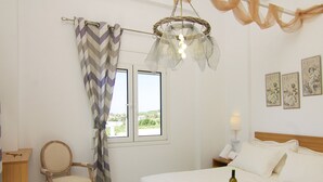 Ett sovrum med en säng, en stol, ett skrivbord och ett fönster med gardiner.