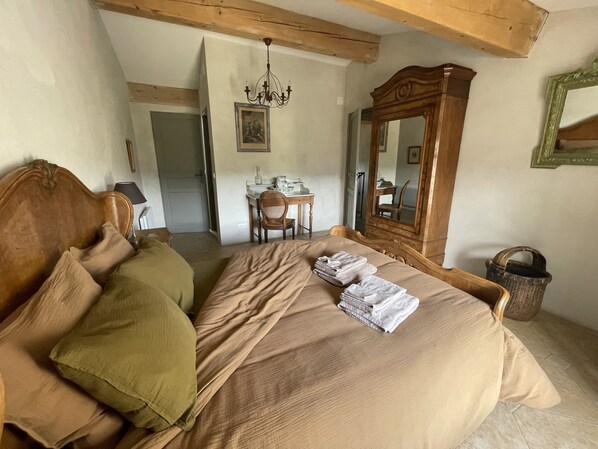 Une chambre à coucher avec un lit en bois, un bureau, une chaise, un lustre et un miroir.