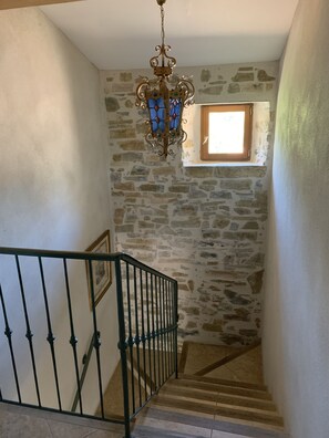 A staircase with stone walls, a metal railing, and a stained glass chandelier. - Gîte-Deluxe-Countryside view-Ensuite (Servies-en-Val)