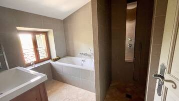 Een badkamer met een bad, douche en wastafel.