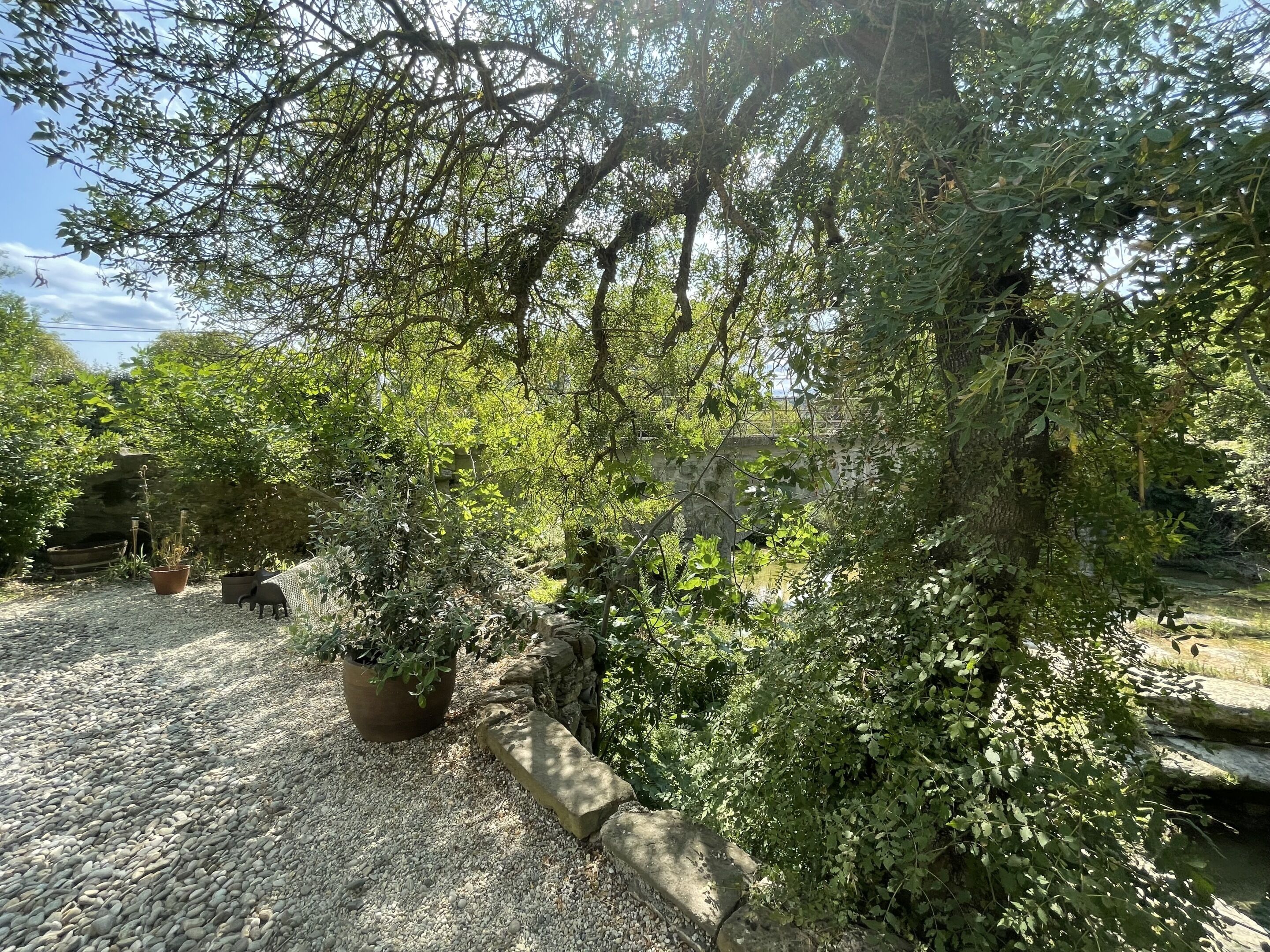 Un espace jardin aménagé avec des plantes en pot, un chemin de gravier et un mur en pierre.