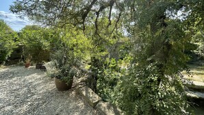 Un espace jardin aménagé avec des plantes en pot, un chemin de gravier et un mur en pierre.