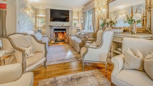 A spacious living room with a fireplace, elegant furniture, and a large mirror. - 8 bedroom accommodation in Horsemans Green (Horsemans Green)