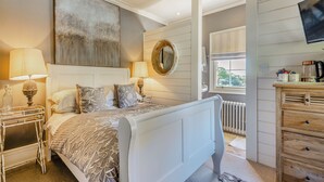A bedroom with a bed, bedside tables, a mirror, a dresser, and a television. - 8 bedroom accommodation in Horsemans Green (Horsemans Green)