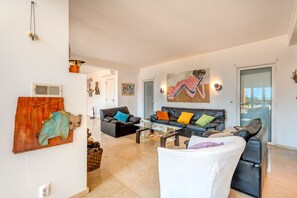 A spacious living room with a sofa set, a coffee table, and a large painting on the wall. - Stay in the property of your dreams at Meia Lua in Pinheiro (luz de tavira)
