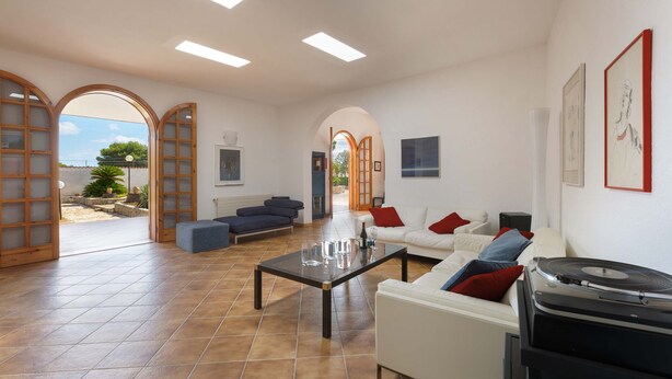 Een ruime woonkamer met een modern design, met een grote salontafel, twee banken en een platenspeler.