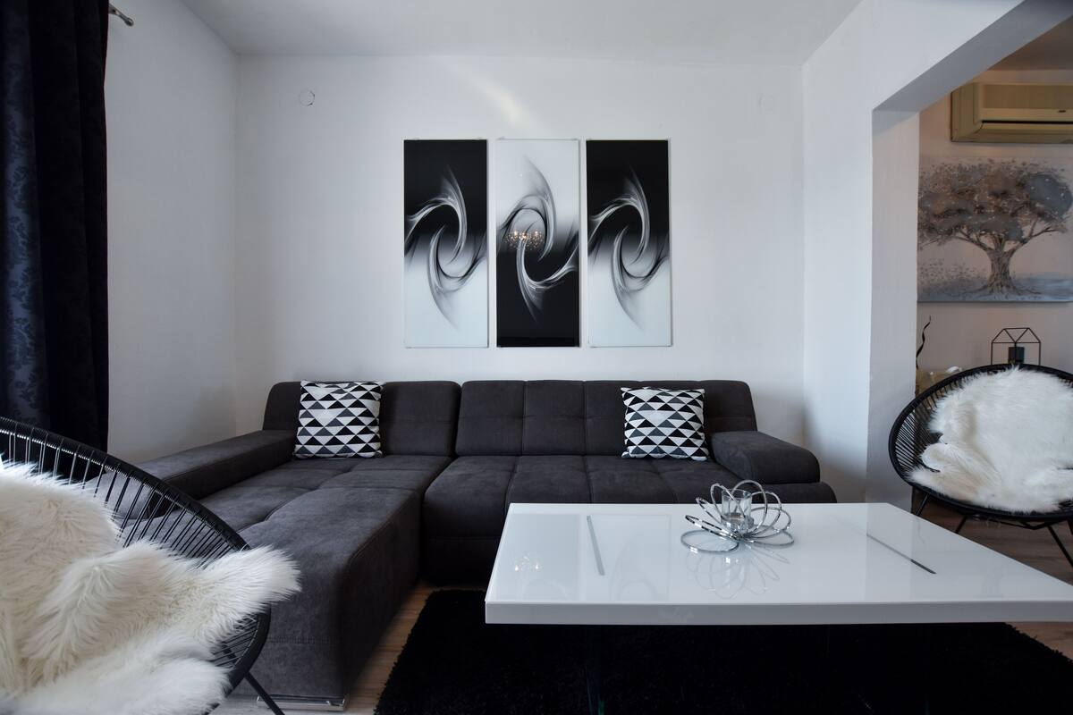 A modern living room with a grey sectional sofa, a white coffee table, and abstract wall art.
