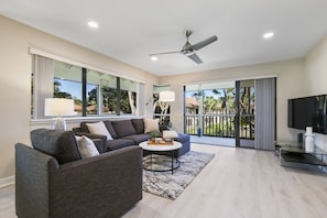 A modern living room with a grey sofa, a coffee table, and a flat-screen TV.