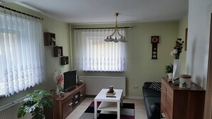 Una sala de estar con televisor, sofá, mesa de centro y plantas en macetas.