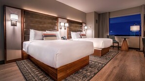 Een hotelkamer met twee bedden, een bureau en een groot raam.
