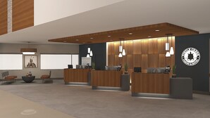 Een modern receptiegebied met houten receptiebalies, hanglampen en een logo aan de muur.