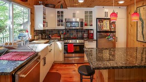 A modern kitchen with stainless steel appliances, wooden cabinets, and a granite countertop.