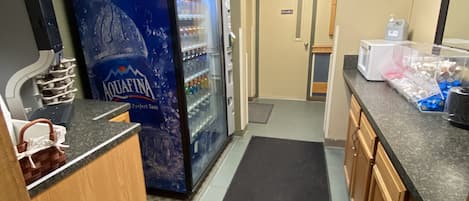 A kitchen with a refrigerator, microwave, and a water dispenser.