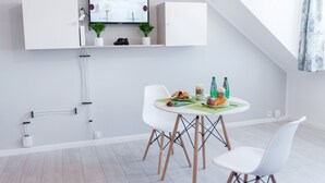 A modern, minimalistic dining area with a white table, chairs, and a flat-screen TV mounted above. - Apartment Centrum (Szczecin)